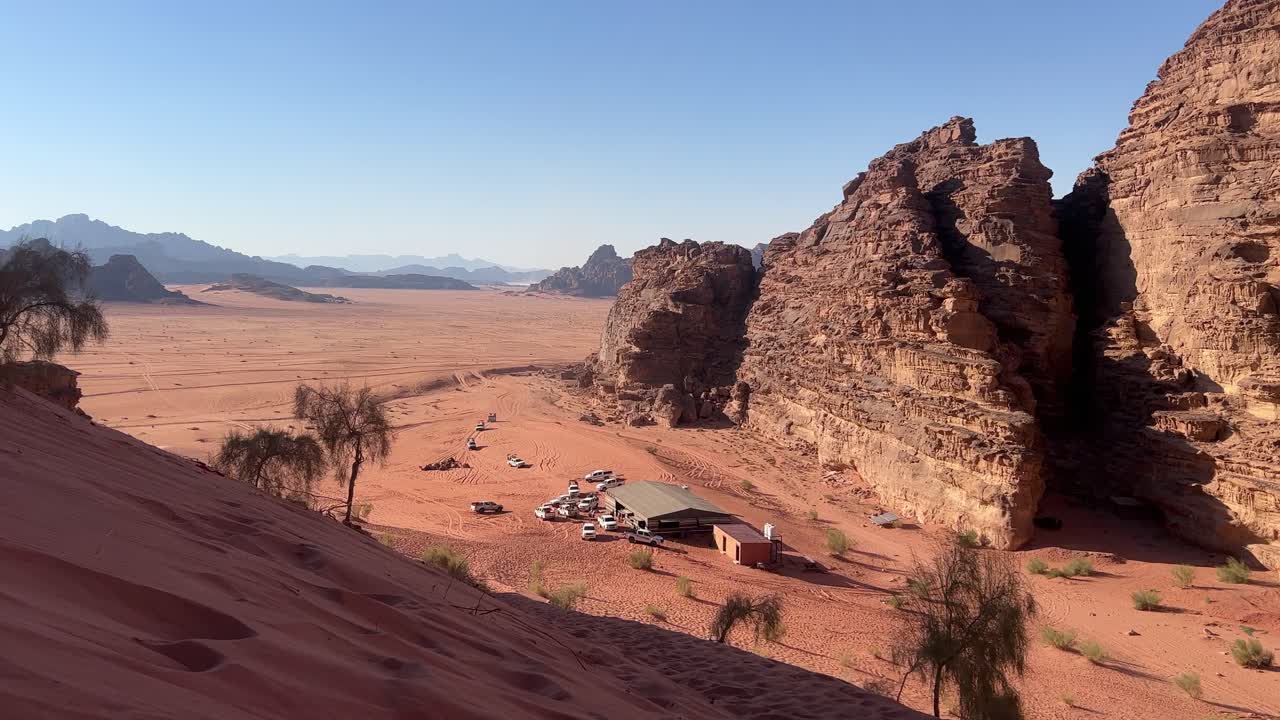 Et bredt oversigtsskud af den enorme røde ørkensand i Wadi Rum, med en beduinlejr i Jordan. 4K stabil optagelse.