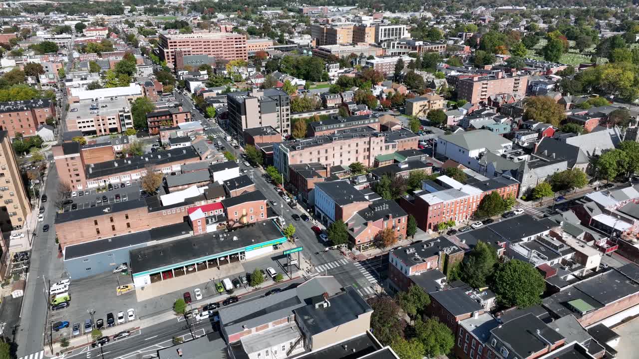 Downtown Main Street with buildings during sunny Day in Lancaster, Pennsylvania. Aerial approaching wide shot. Cars between houses and homes in autumn season