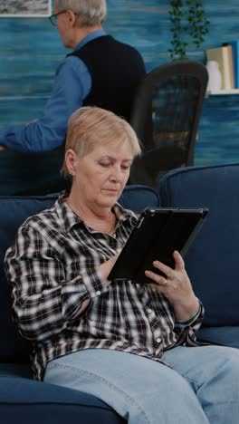 vertical video: happy old senior grandmother holding digital tablet browsing informations