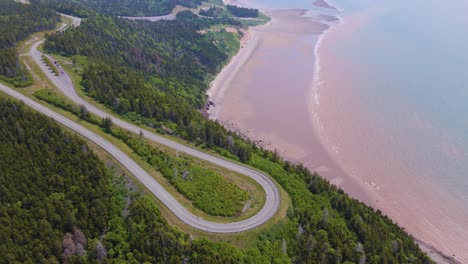 drone shot panning upwards slowly revealing the beautiful landscape in new brunswick of the famous bay of fundy trail parkway with the stunning coastline in the background during a hot summer day