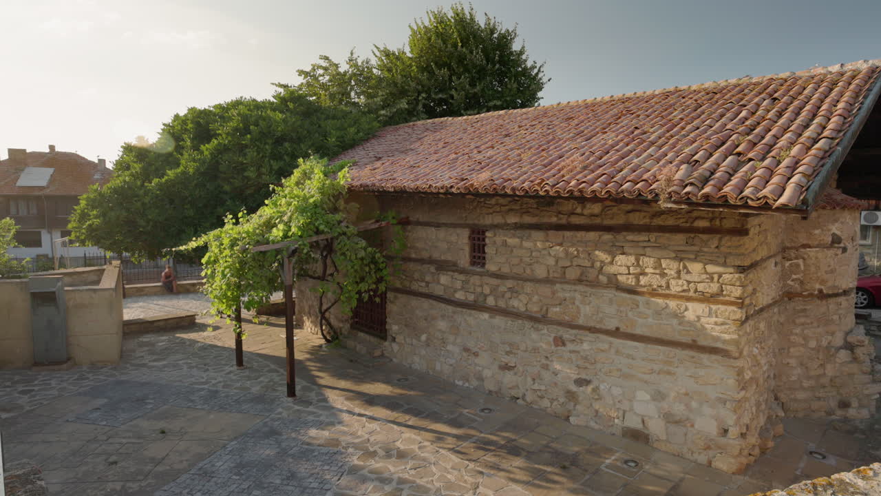 Casa storica in pietra con tetto in tegole e viti verdi nell'antica Nessebar.