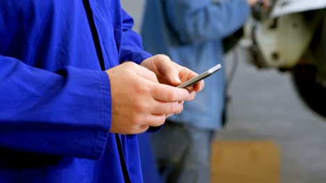 mechanic using mobile phone in garage 4k