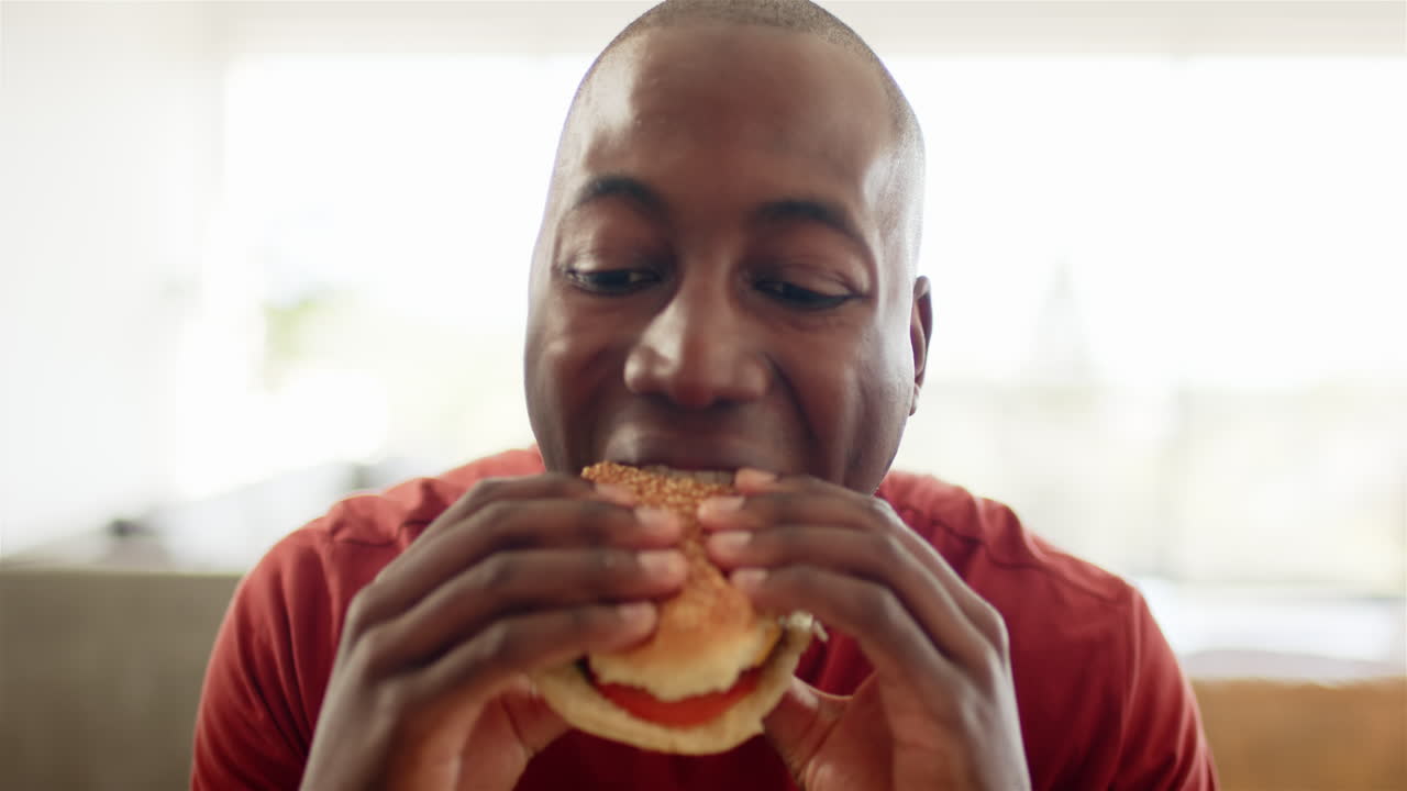Eating burger, man enjoying delicious meal with smile