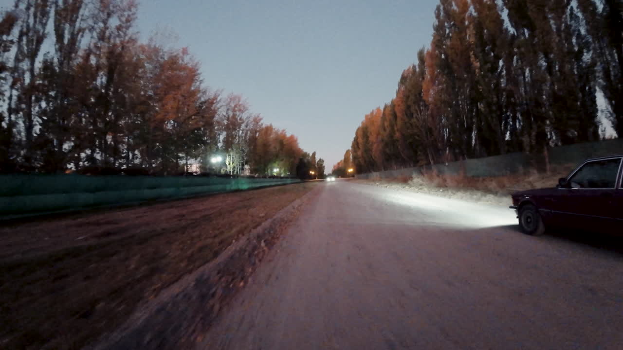 Auto parcheggiata su strada sterrata rurale al tramonto mentre un'altra auto passa