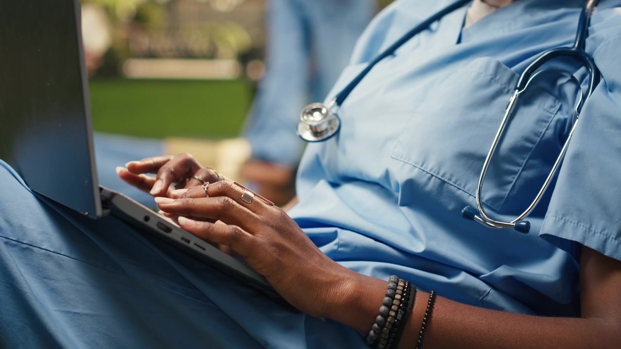 Primo piano di uno studente di medicina che digita sulla tastiera di un laptop seduto su un pouf a sacco