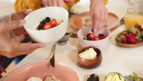 eating breakfast together, multiracial senior couple enjoying fresh fruit and bread at home