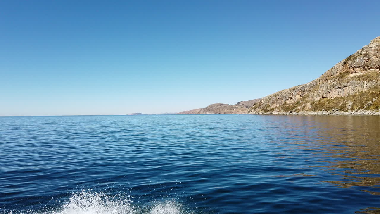 Boat ride in Puno lake Titicaca Peru land view of taquille island with blue sky