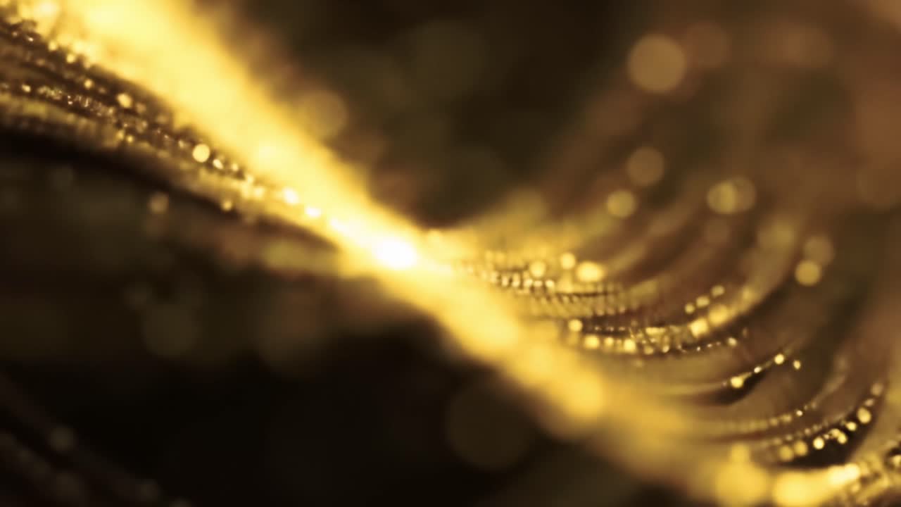 Golden particles elegantly flow and shimmer, creating a captivating display of light and movement. The visual showcases the beauty of fluid dynamics and highlights the interplay of colors.