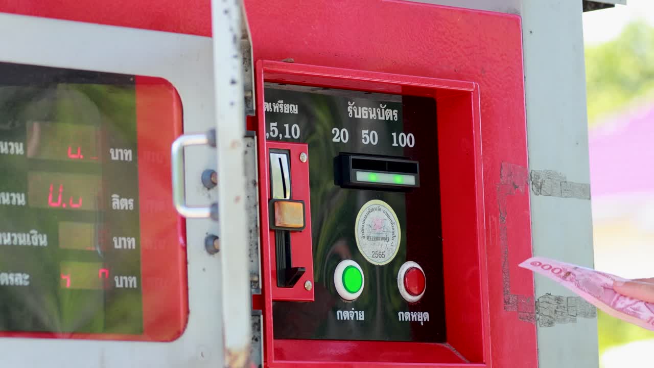 A person interacts with a fuel vending machine, inserting currency and selecting options under bright daylight