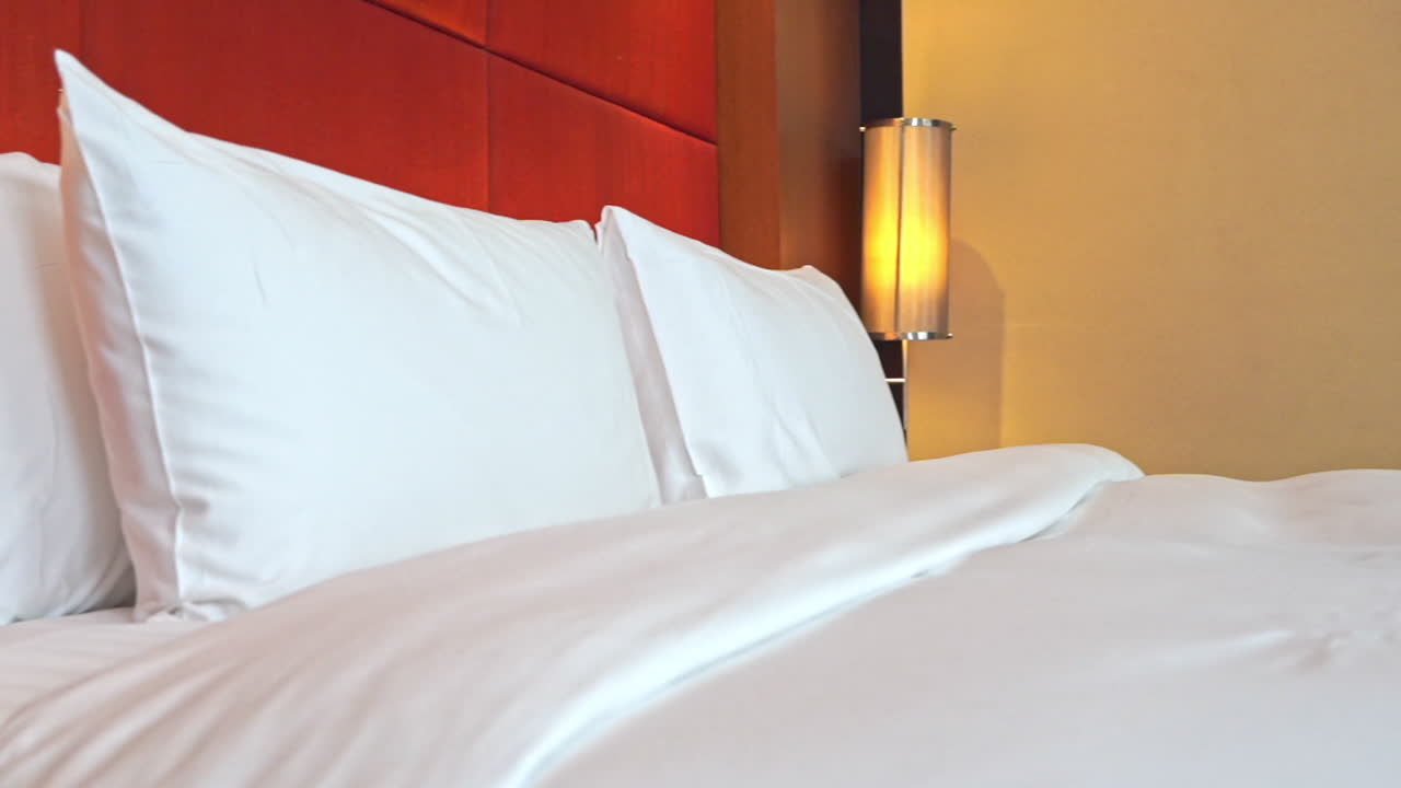 cómoda cama doble con cabecero rojo y blanco y sábanas claras