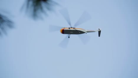 firefighting helicopter flies low overhead searching for water for nearby raging forest wildland fire