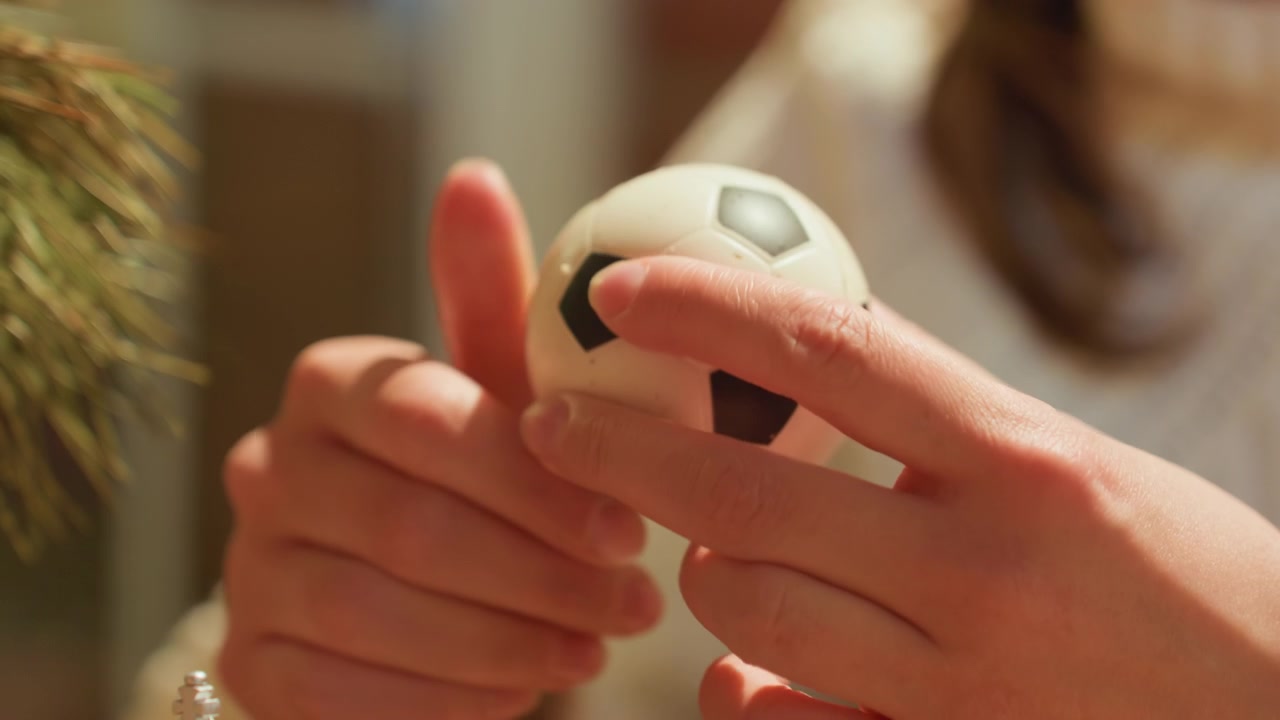 Primo piano di mani che stringono un antistress a forma di piccolo pallone da calcio.
