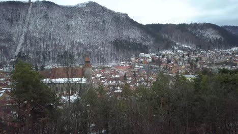 Aerial-View-Of-Medieval-Church-And-Town-With-Mountain-During-Winter-Season-In-Romania