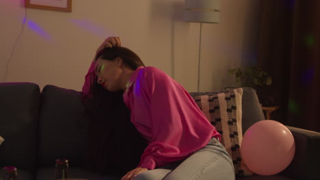 집 파티에서 술을 마신 후 회복하는 소파에 앉아있는 여성은 숙취로 고통받고 있습니다.