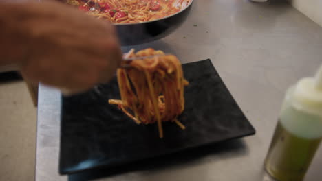 chef grabbing spaghetti with lobster from the pan and plating the gourmet dish
