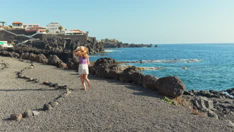 caucasian girl in summer clothes running slowmo on pebbles beach along coast