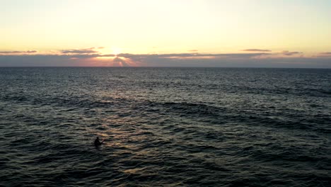 sunset drone shot of surfers catching waves on praia do guincho on cascais - sintra