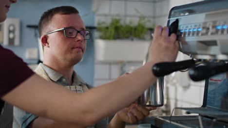 Kaukasischer-Mann-Mit-Down-Syndrom-Als-Kellner,-Der-Der-Kellnerin-Beim-Kaffeekochen-Hilft.