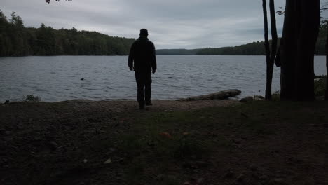 wide shot of person entering frame and arriving at the shore of macdonald lake
