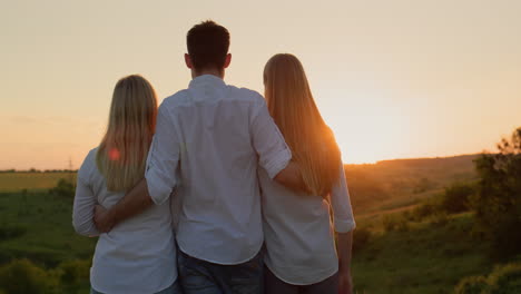 a group of friends enjoy the sunset over a picturesque valley, rear view