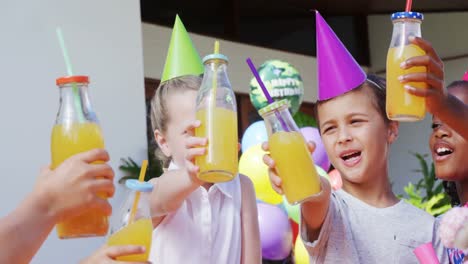 niños brindando las botellas de jugo en el patio trasero de la casa 4k