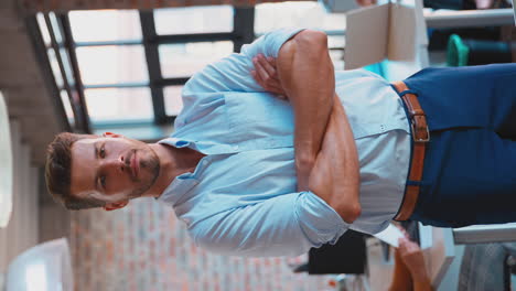 Vertical-Video-Portrait-Of-Businessman-With-Serious-Expression-In-Busy-Office-With-Colleagues