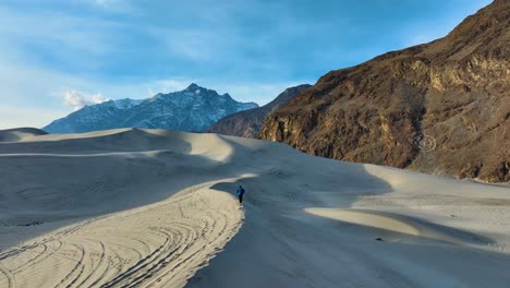 Rear view of a tourist running and exploring on sand dunes of Sarfaranga Cold Desert in Skardu Valley, Pakistan