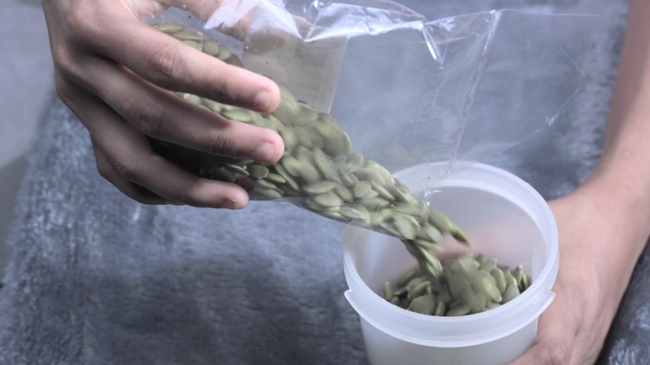 girl Pumpkin seeds are placed in a container closeup view