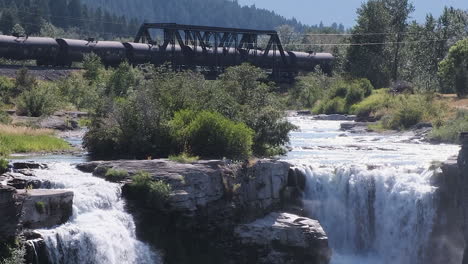 cinemagrafía creativa del tren cp rodando antes de una cascada inmóvil