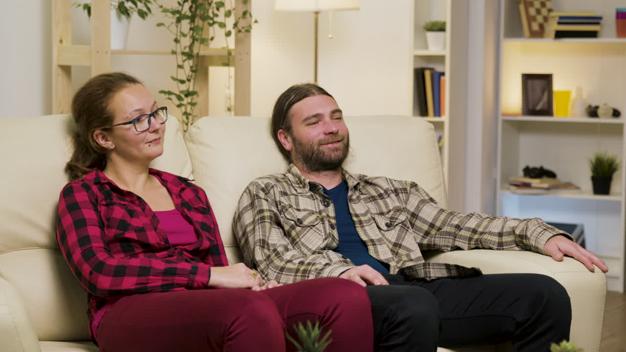 부부는 집에서 소파에서 휴식을 취하고 있습니다.