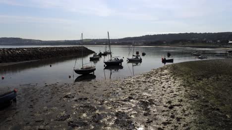 Aerial-view-boats-in-shimmering-low-tide-sunny-warm-Rhos-on-Sea-seaside-sandy-beach-marina-coastline-orbit-low-right