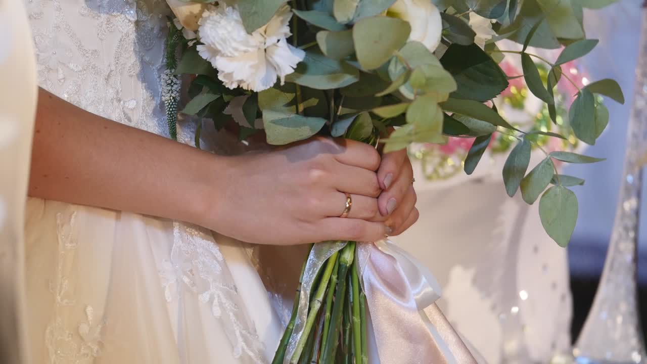 Bellissimo bouquet da sposa nelle mani di una giovane sposa vestita con un abito da sposa bianco. Primo piano di un grande mazzo di rose bianche fresche e tulipani nelle mani femminili. Sposa anonima che tiene i fiori