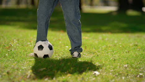 Männliche-Beine-Treten-Ball-Auf-Der-Grünen-Wiese-Im-Sonnigen-Park-In-Nahaufnahme.-Aktives-Sommerwochenende.