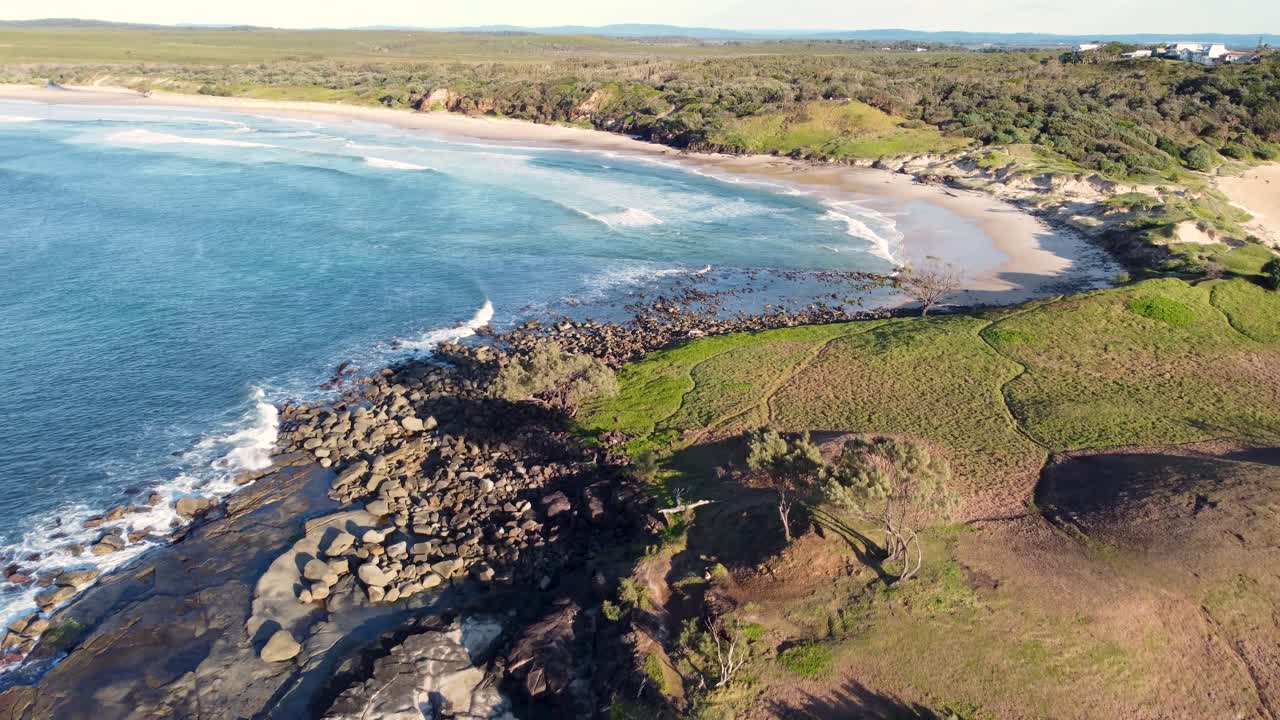 toma panorámica aérea de drones de arrecife de isla playa rocosa lugar de surf hermosa vista de la naturaleza bushland promontorio yamba angourie costa norte nsw australia 4k