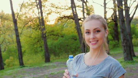 attractive woman drinks water from a bottle in the park