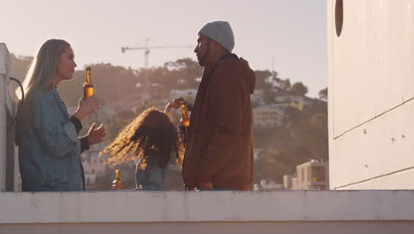 group-of-multi-ethnic-friends-hanging-out-enjoying-rooftop-party-chatting-drinking-alcohol-having-fun-socializing-on-weekend-reunion-celebration-at-sunset