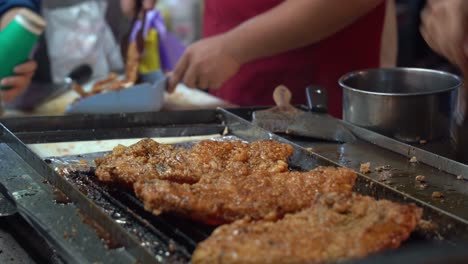 delicious appetizing honey soy coated fried chicken fillet grilling on hot grill, professional chef brush tasty sauce on the meat with aromatic smell at famous night market, taiwan, asia