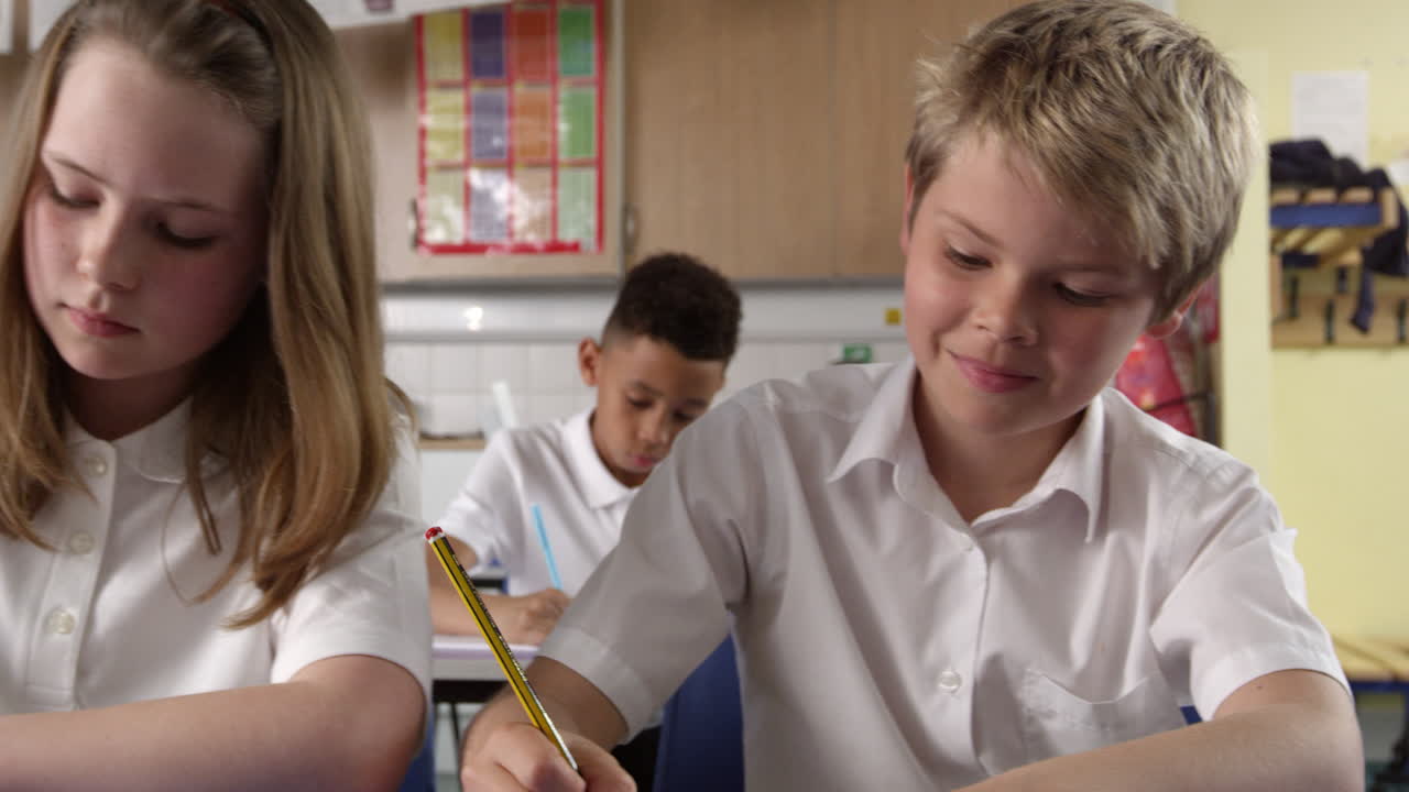 primer plano de los alumnos que trabajan en los escritorios en el aula filmado en r3d