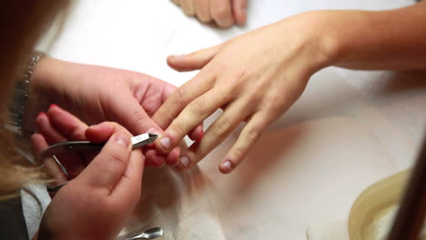 nail technician removing cuticles from customers nails