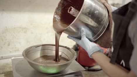 mujer de la cosecha vertiendo chocolate derretido en un cuenco de escala