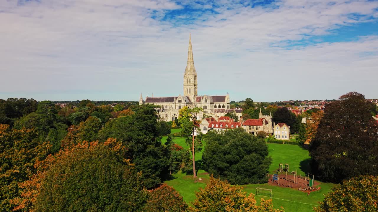 Aerial drone view of Salisbury Cathedral rising above colourful trees and historic buildings in Salisbury, Wiltshire, England. Scenic view of one of the UK's most famous medieval cathedrals