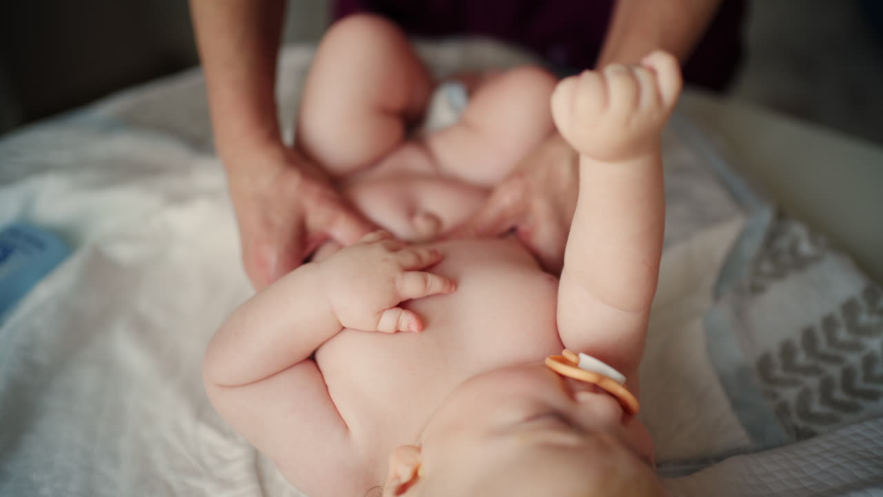 Bambino sdraiato sulla schiena mentre un adulto lo massaggia ed esegue esercizi di mobilità.