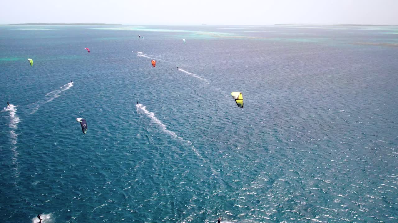 다채로운 카이트 서퍼가 고 푸른 물 위를 날아다니며, 활기차고 역동적인 바다 풍경, 공중 풍경
