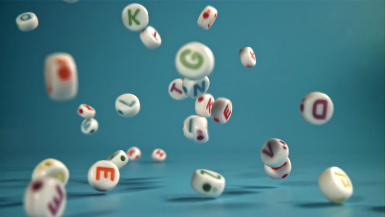 Slowmotion af alfabetperler, der falder på blå baggrund