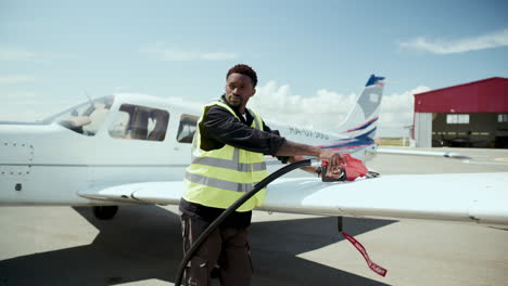 african american ground technician refueling aircraft wing tank on airfield
