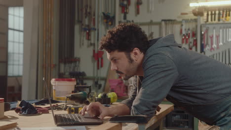 woodworker using laptop in carpentry workshop