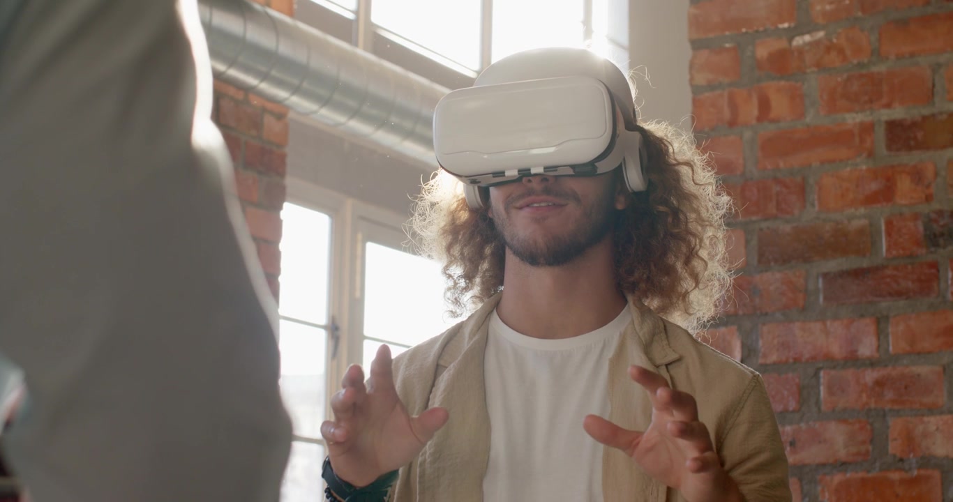Colleghi che osservano un uomo afroamericano che indossa un visore VR dopo un input, mentre esegue un gesto di pizzico in un loft.
