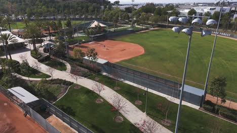stadium lights over vibrant baseball diamond. empty field on a sunny day. pitching machine set up for adult recreational softball lake forest, california.