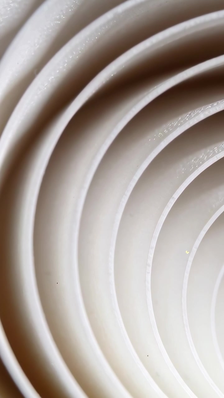 Vertical video: Camera nudging concentric white sheets sliding across studio, revealing inner arcs