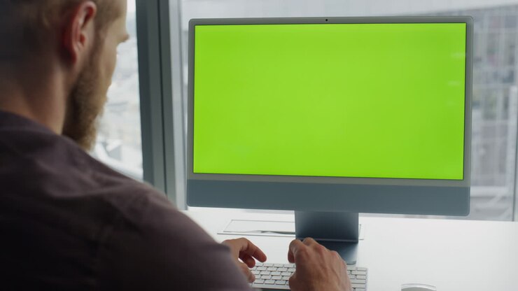Programmør taster på chromakey-tastatur på kontoret. Udvikler koder på grøn skærm pc.